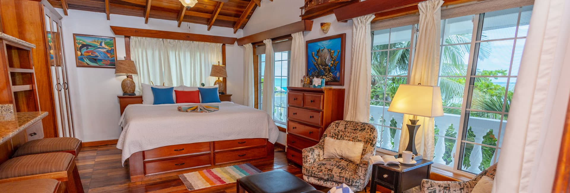 Cozy bedroom with a wooden ceiling, large windows, and colorful decor.